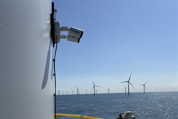 Ein Blick vom Offshore-Windpark mit Windrädern im Hintergrund und klarem Wasser im Vordergrund.